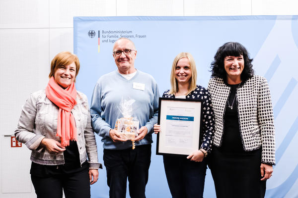 In Berlin &uuml;bergaben Caren Marks (links) und Prof. Dr. Karin B&ouml;llert (rechts) die Urkunde an Klaus Neusius und Jenny Lauer. Foto: "Andi Weiland | Arbeitsgemeinschaft f&uuml;r Kinder- und Jugendhilfe - AGJ"
