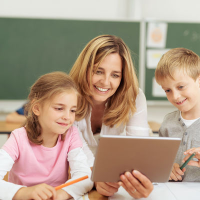 lehrerin zeigt kindern etwas am tablet